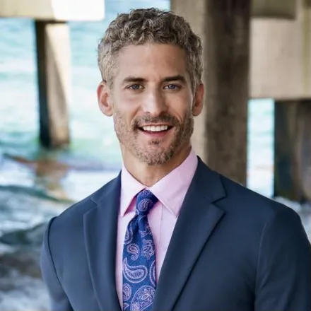 Anthony Gatta, CEO and founder of Gatta Insurance, photographed in a navy suit on a waterfront pier